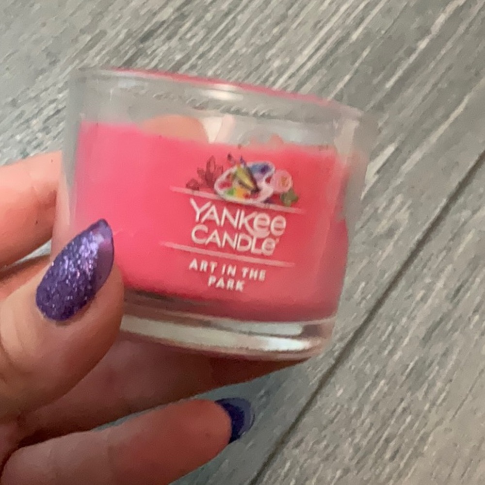 A pink candle that is scented like flowers and vanilla and a bit of cinnamon